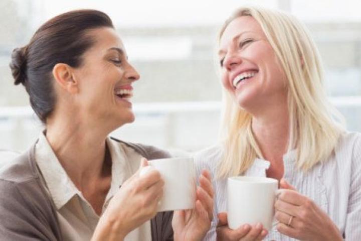 Cheerful women gossiping while having coffee in living room