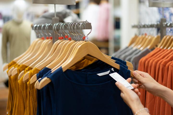 Una persona, mirando la etiqueta de una prenda de ropa en una tienda.