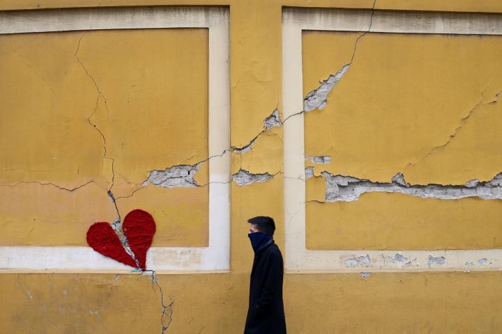 A man walks next to a repaired broken heart made of wool by Croatian designer Ivona, put on a building in downtown Zagreb, Croatia, March 25, 2020, as the country is fighting coronavirus disease (COVID-19) outbreak and the aftermatch of an earth...