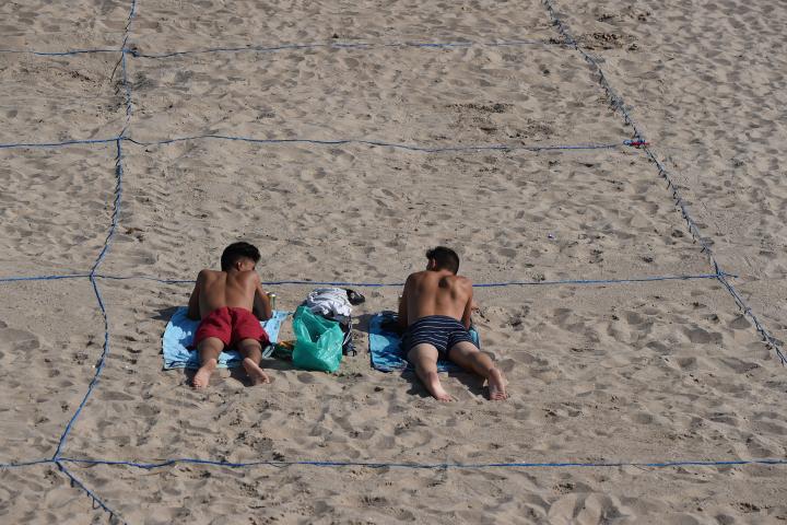 BENIDORM, SPAIN - JUNE 16:  Two young men sunbathe in their designated roped-off area on Poniente beach a day after the town's beaches were reopened after three months of closure due to the coronavirus pandemic on June 16, 2020 in Benidorm, Spai...