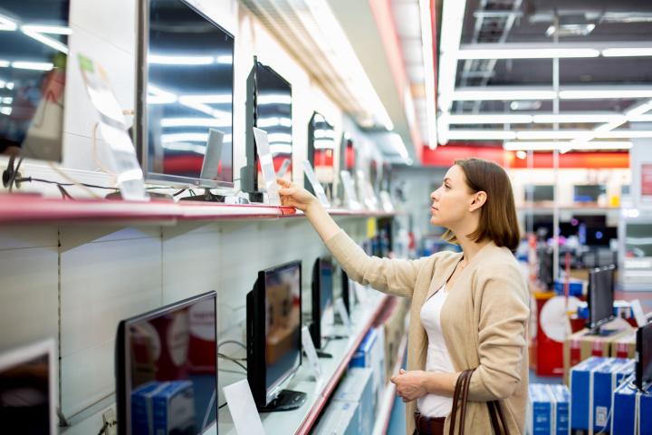 Una mujer mirando televisiones en una tienda de electrónica.