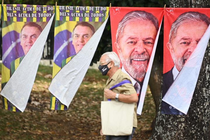 Un hombre cruza ante los carteles de Bolsonaro y Lula para las elecciones en Brasil.
