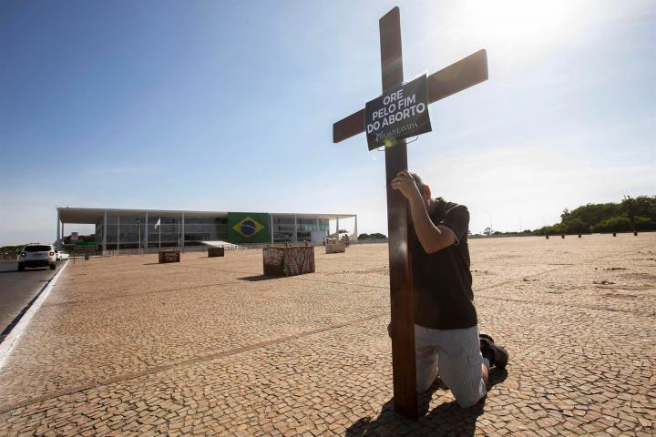 Un hombre mientras reza con una cruz, en la Plaza de los Tres poderes, en Brasília