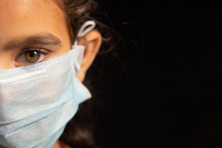 young girl child with medical mask wearing, protection against covid 19 or coronavirus pandemic on black background with copy space