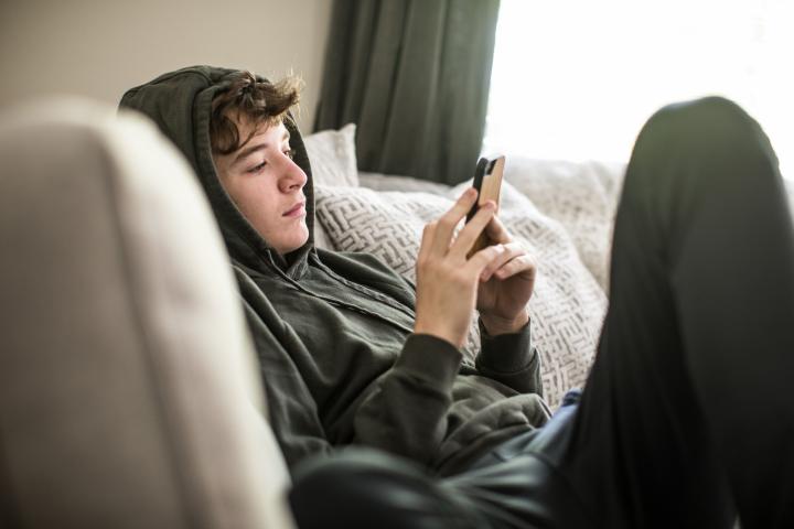 Un adolescente usando un teléfono.