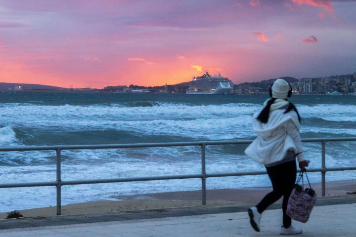 Una mujer pasea este lunes por la cala San Vicens, en Palma de Mallorca, ante la inminente llegada de la borrasca Denise.