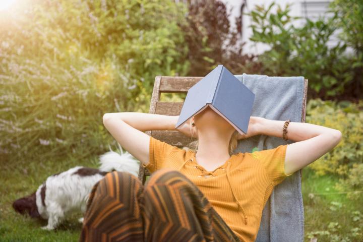 Una mujer tapándose el sol con un libro.