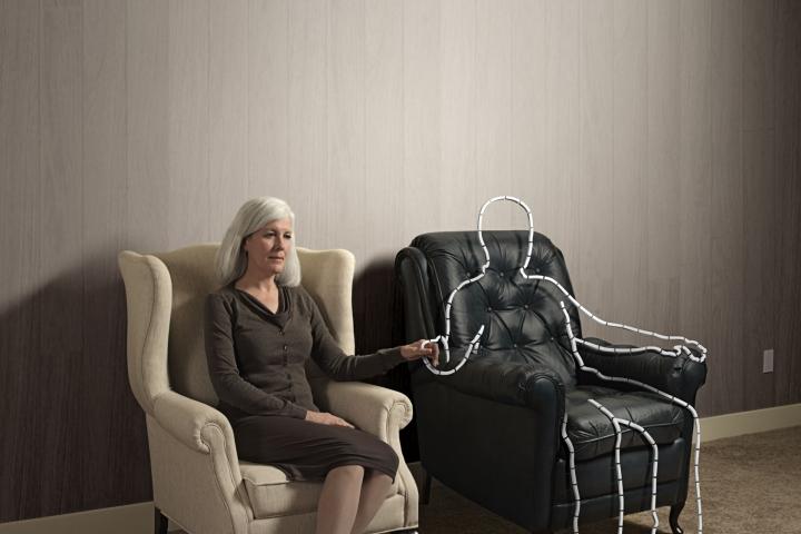 Woman sitting in chair holding hand of outlined male shape