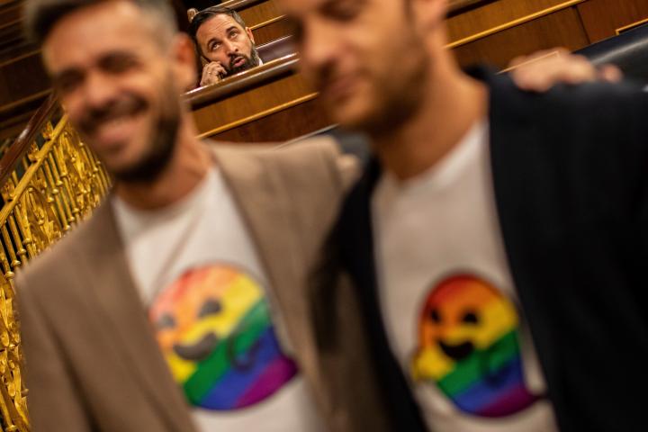 Socialist lawmakers dressed with a t-shirt bearing an emoji with the rainbow flag pose for the media in front far right Vox party leader Santiago Abascal, background, at the Spanish parliament in Madrid, Spain, Tuesday, May 21, 2019. The icon ha...
