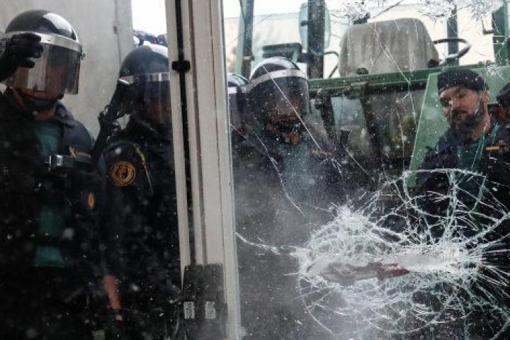 Policías y guardias civiles rompen una puerta de cristal para entrar en un colegio electoral el 1 de octubre.