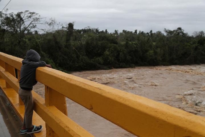 Un niño observa la crecida del río Chavón tras el paso del huracán Fiona