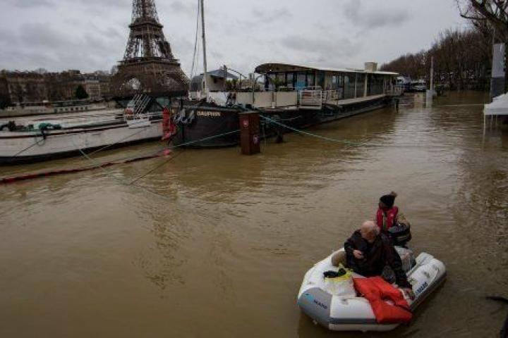Varias personas usan lanchas para ser evacuadas en el Sena, con la Torre Eiffel de fondo.