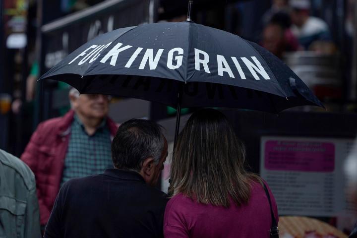 Una pareja se protege de la lluvia con un paraguas en una calle del centro de Oviedo.