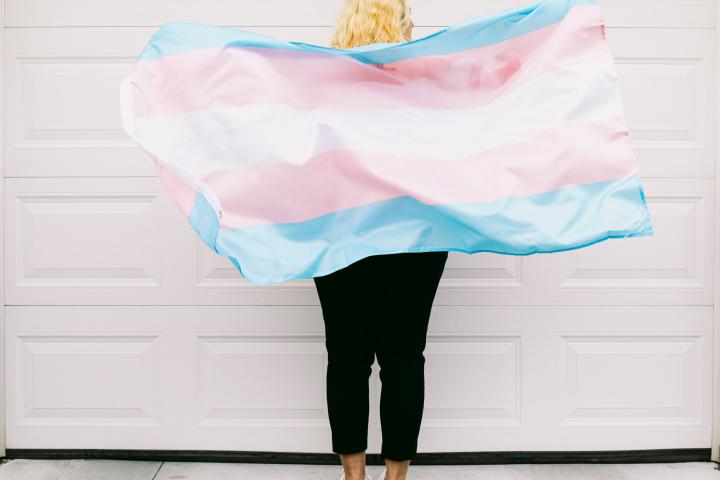Persona trans junto a la bandera del colectivo.
