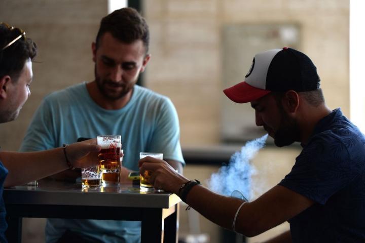 Un hombre fuma mientras bebe una cerveza en una terraza de un bar en Sevilla.