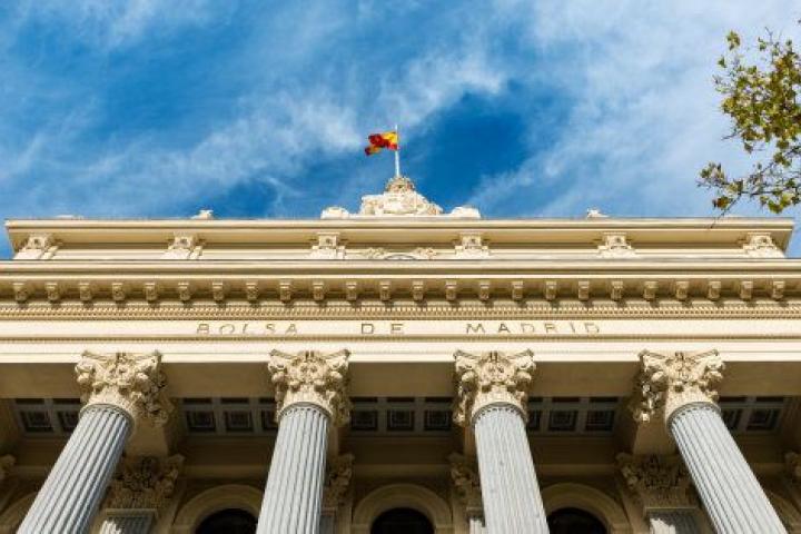 Madrid, Spain - September 25, 2015: Low-angle view of the columns and neoclassical facade of the Bolsa de Madrid (Madrid's Stock Exchange) against a cloudy blue sky.