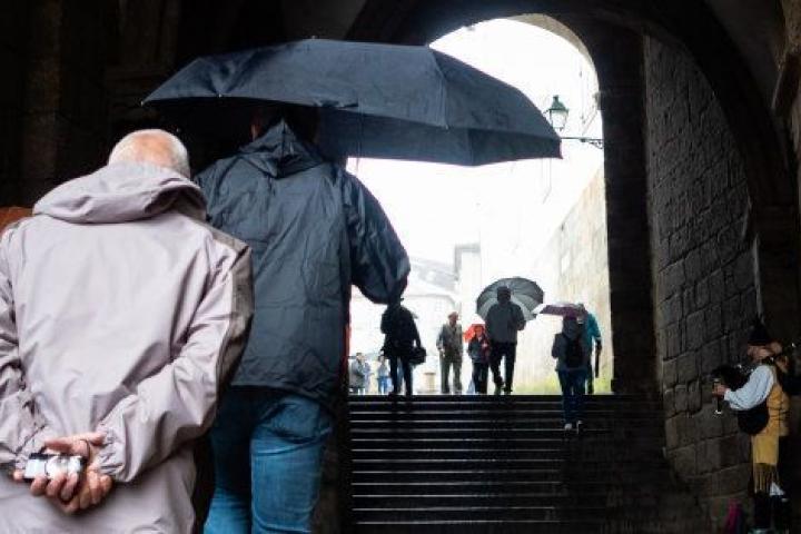 Un grupo de turistas con paraguas accede a la Plaza del Obradoiro de Santiago, en una imagen de archivo.