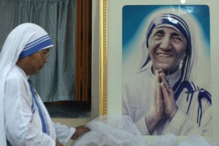 TOPSHOT - A nun of ?the Missionaries of Charity decorates a picture of Mother Teresa prior to a special prayer service at Mother House in Kolkata on December 18, 2015.   Mother Teresa, set to become a saint after the Vatican announced recognitio...