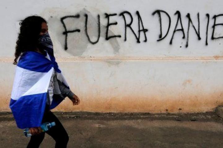 Una joven manifestante pasa ante una pintada contra Daniel Ortega, el pasado 25 de agosto en Granada, Nicaragua.