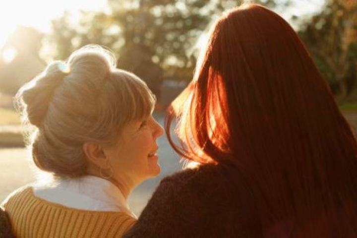 Rear view of senior woman and adult daughter strolling in park
