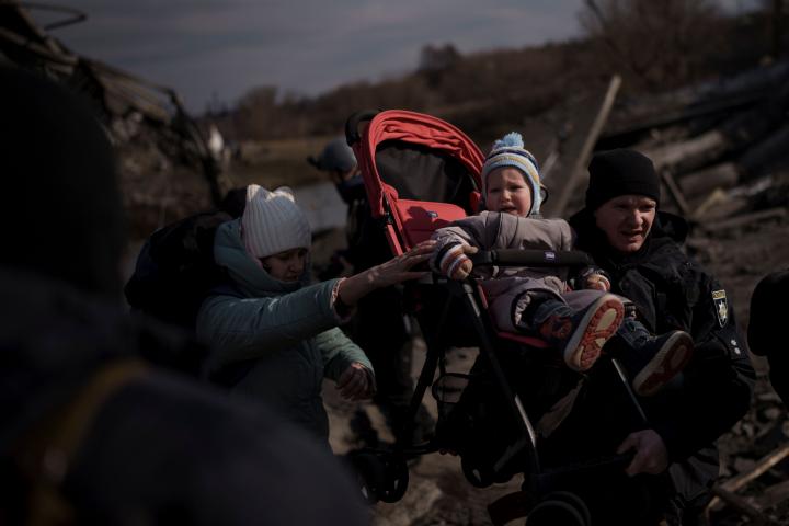 Un niño es trasladado en un carrito por una senda improvisada mientras huye de Irpin, a las afueras de Kiev, Ucrania, el miércoles 9 de marzo de 2022.