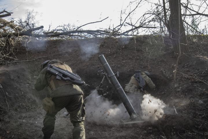 Los militares ucranianos se ponen a cubierto mientras disparan una carga de mortero en la línea del frente de Toretsk en Donbas, Ucrania. 