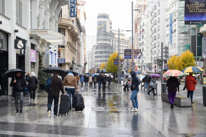 Varias personas caminan con paraguas en la Gran Vía de Madrid. 