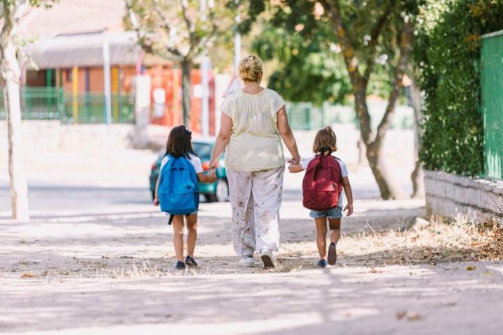 Una madre acompaña a sus hijas al colegio.