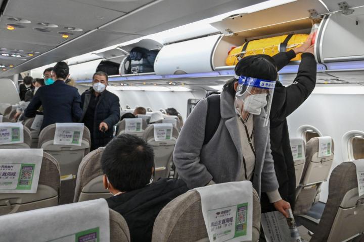 Varios pasajeros con pantallas de protección en un avión en China
