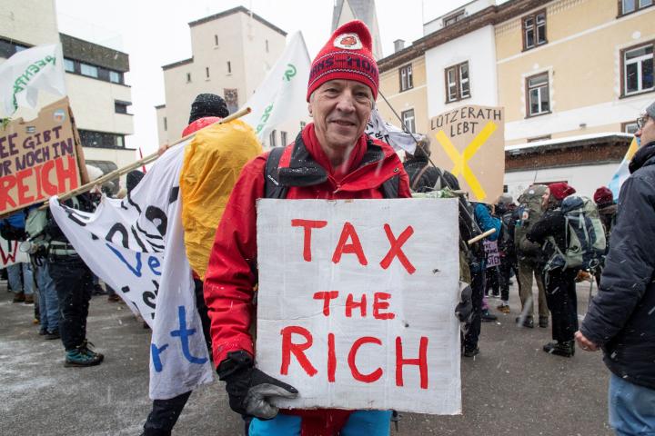 Un activista posa en Davos con una pancarta en la que pide tasas a los más ricos