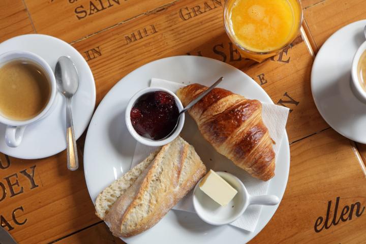 Café, tostada, croissant y zumo en un desayuno.