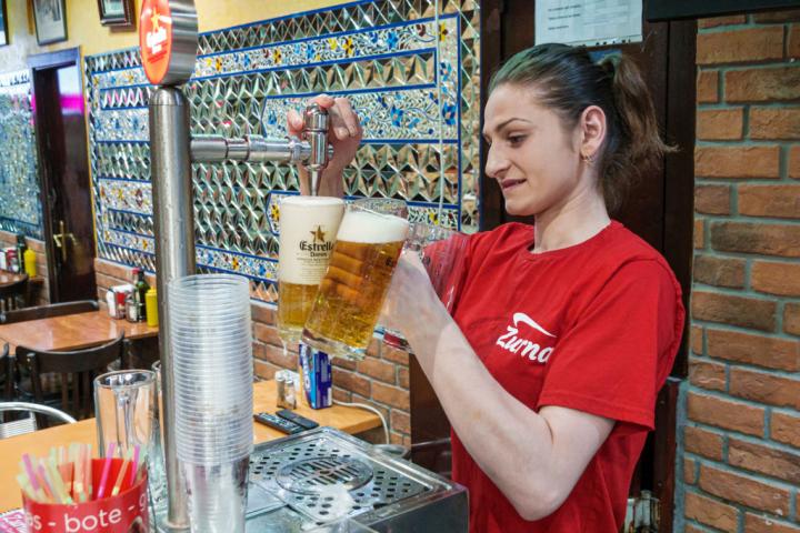 Una trabajadora de un bar sirve una cerveza en Barcelona.