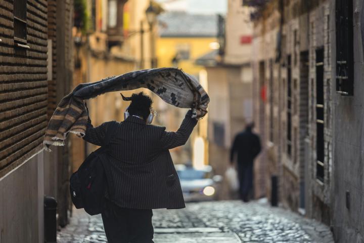 Una persona se echa una prenda de abrigo sobre los hombros mientras camina por una calle de Toledo este lunes.