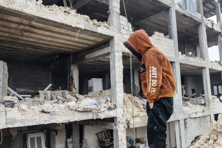 Un joven observa un edificio destrozado por el terremoto