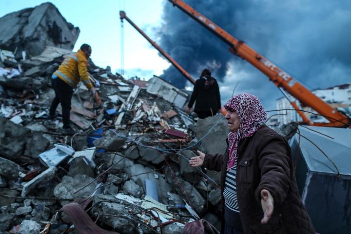 Mujer junto al personal de emergencia que busca en los escombros en Hatay (Turquía).