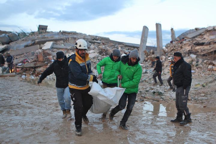 Rescatadores sirios portan un cuerpo rescatado de los escombros en la ciudad de Sarmada, ayer.