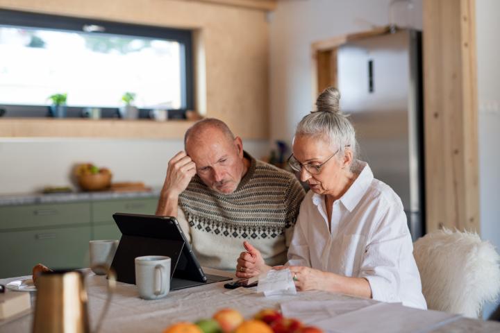 Una pareja de personas mayores, consultando el ordenador.