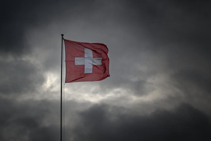 La bandera de Suiza bajo un cielo nublado en Ginebra.
