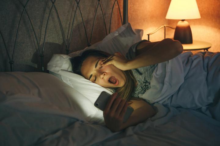 Imagen de archivo de una mujer bostezando en la cama.