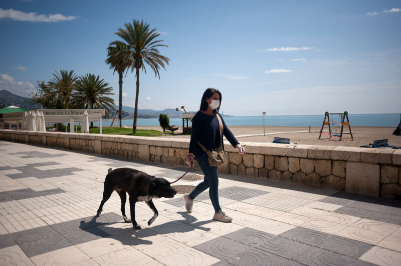 Una mujer pasea con su perro por la playa de la Malagueta (Málaga).