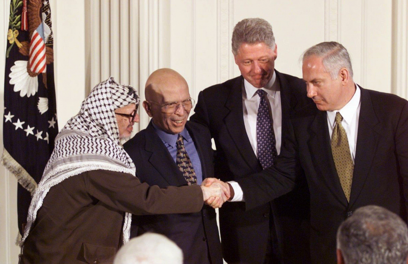 Yasser Arafat y Benjamin Netanyahu se dan la mano, en presencia de Hussein de Jordania y Bill Clinton, tras los acuerdos de Wye Plantation, en 1998.