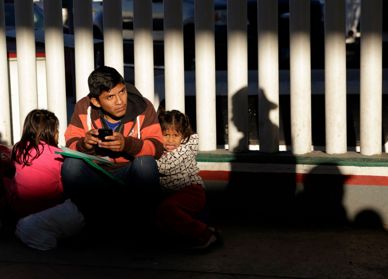 Un migrante sin identificar aguarda con sus hijos para ver si anuncian el número que le corresponde para solicitar asilo en Estados Unidos, el viernes 25 de enero de 2019, en Tijuana, México.