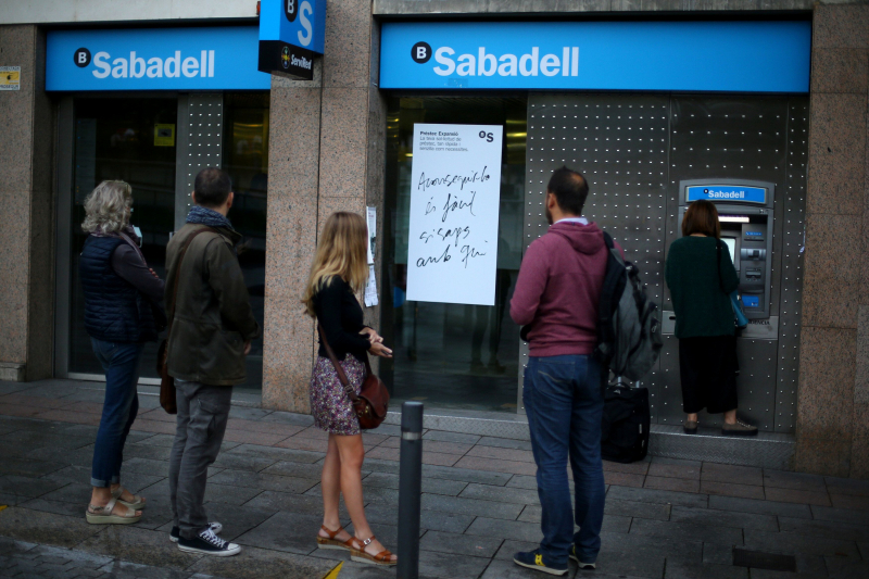 People line up at a Sabadell Bank ATM machine in Barcelona to withdraw money as part of an action to protest the transfer of the bank's headquarters out of Barcelona, Spain, October 20, 2017. REUTERS/Ivan Alvarado