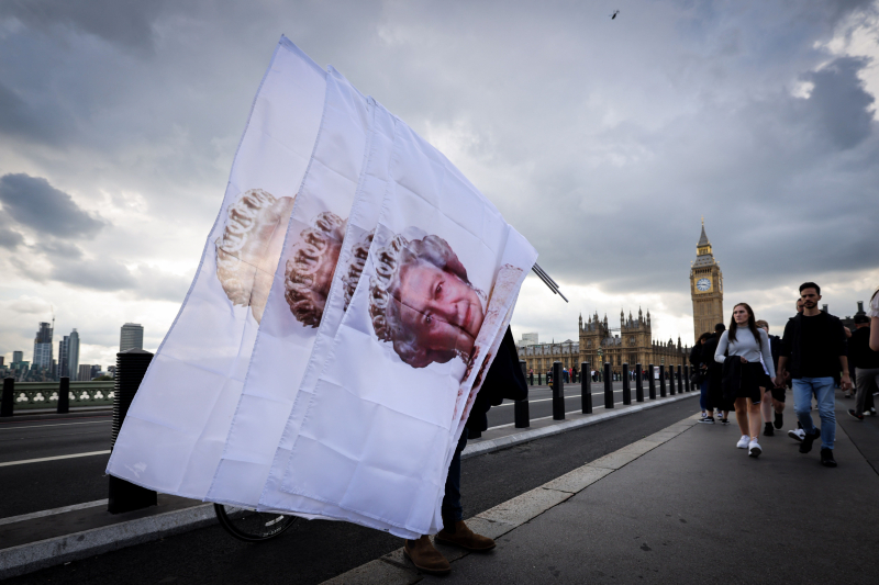 Un hombre vende banderas con el rostro de Isabel II en el Puente de Westminster, a la espera del cortejo fúnebre. 