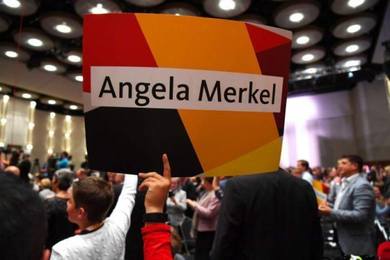 Seguidores de Merkel sujetan carteles con su nombre.