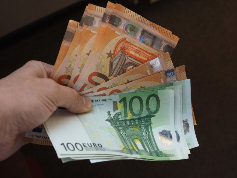 Hand holding and giving Euro banknotes money (EUR), currency of European Union