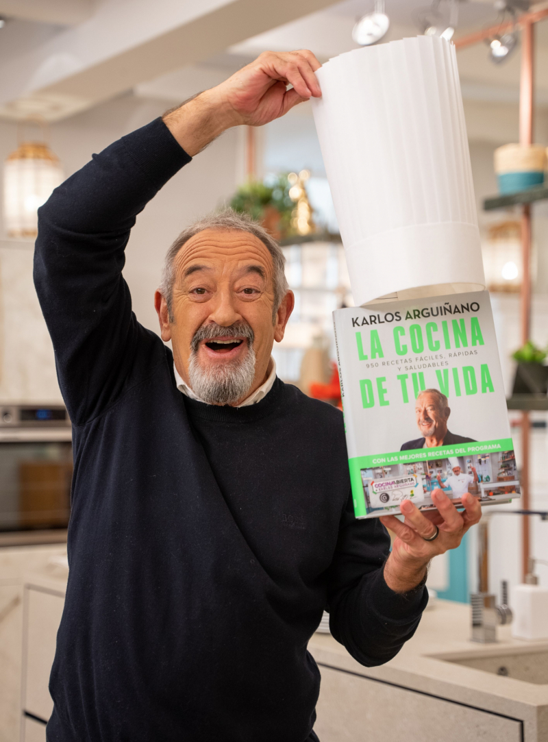 Karlos Arguiñano sostiene una copia de su libro.