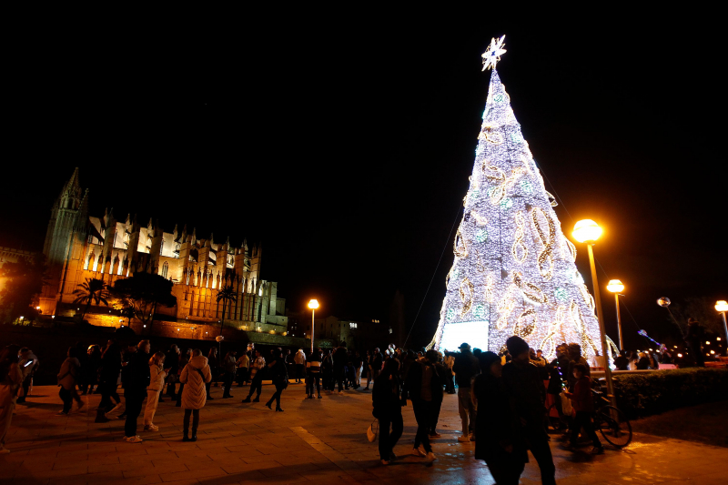 Grupos de personas admiran la iluminación navideña ante la Catedral de Palma de Mallorca.