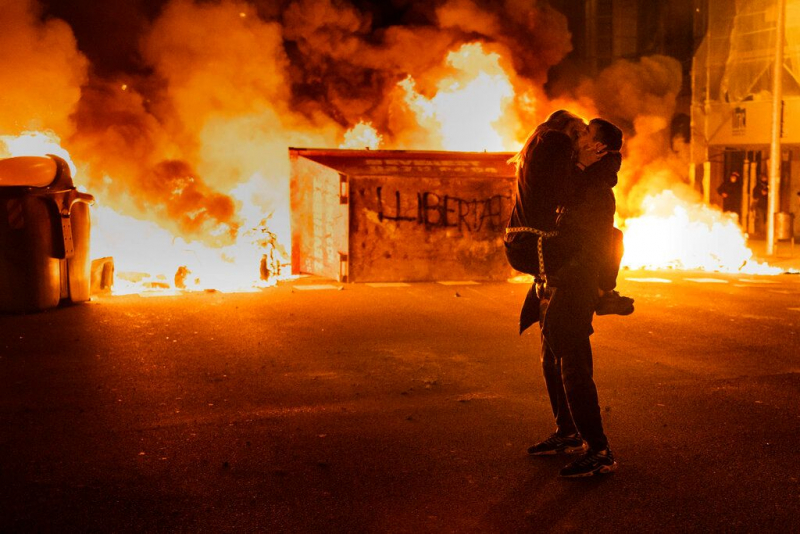 Una pareja se besa frente a una barricada ardiendo, tras los disturbios entre la Policía y los manifestantes que protestaban por el encarcelamiento del rapero Pablo Hasél. En Barcelona, el 18 de febrero de 2021.
