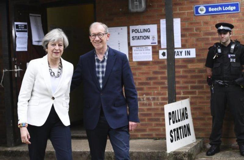 La conservadora Theresa May, actual primera ministra, y su marido, Philip May, antes de votar esta mañana.